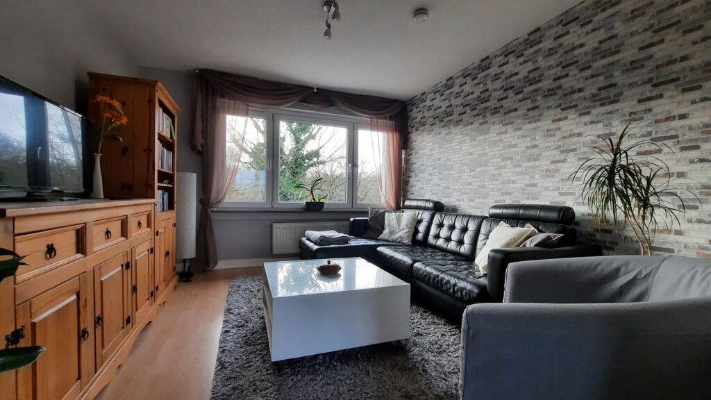 Gemütliches Wohnzimmer in der Ferienwohnung Orsoyerberg mit modernen Möbeln und großem Fenster zur N.